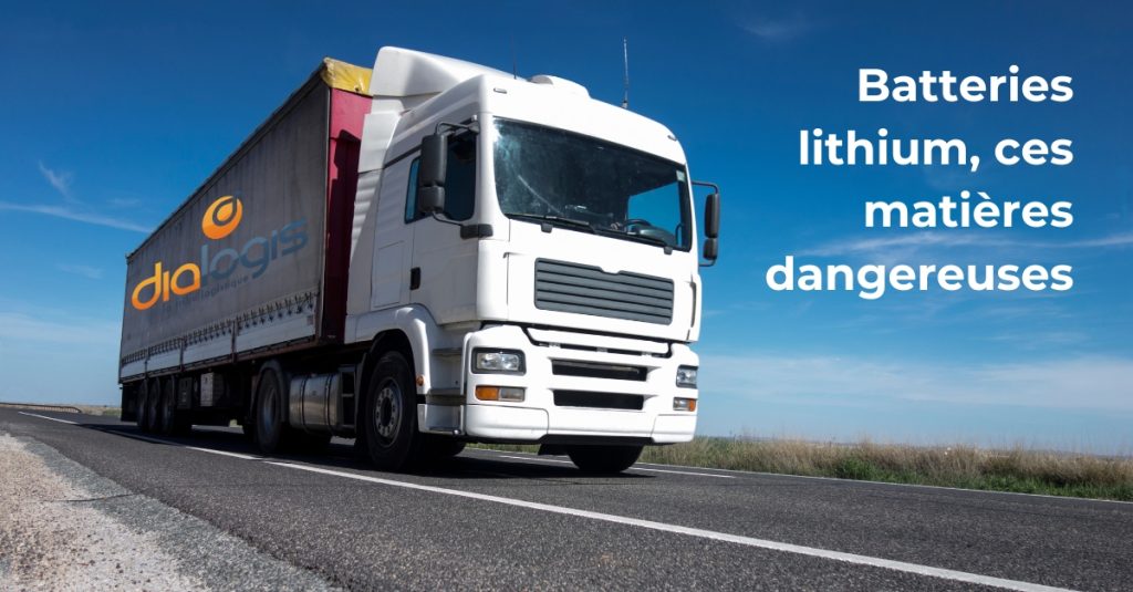 L'image montre un camion blanc roulant sur une route sous un ciel bleu dégagé. La remorque est couverte d'une bâche rouge avec le logo de l'entreprise "Dialogis", spécialisée en transport et logistique.

Sur la droite de l'image, un texte blanc indique :
"Batteries lithium, ces matières dangereuses"

L’ensemble met en avant les enjeux liés au transport des batteries lithium, soulignant leur classification en tant que marchandises dangereuses.